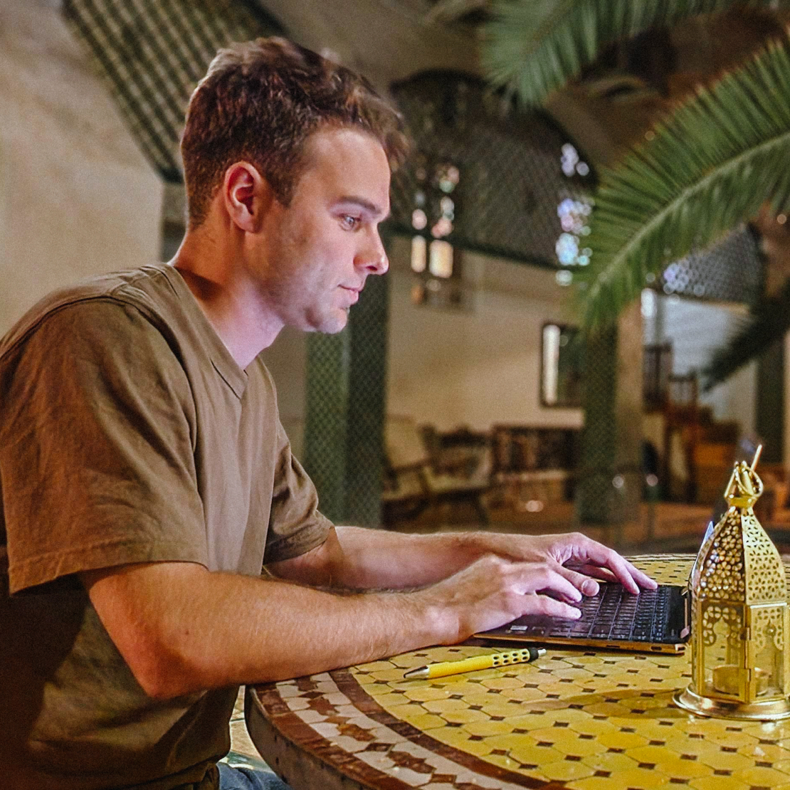 Quentin Lavallée-Bourdeau avec son ordinateur portable posé sur une table au Maroc