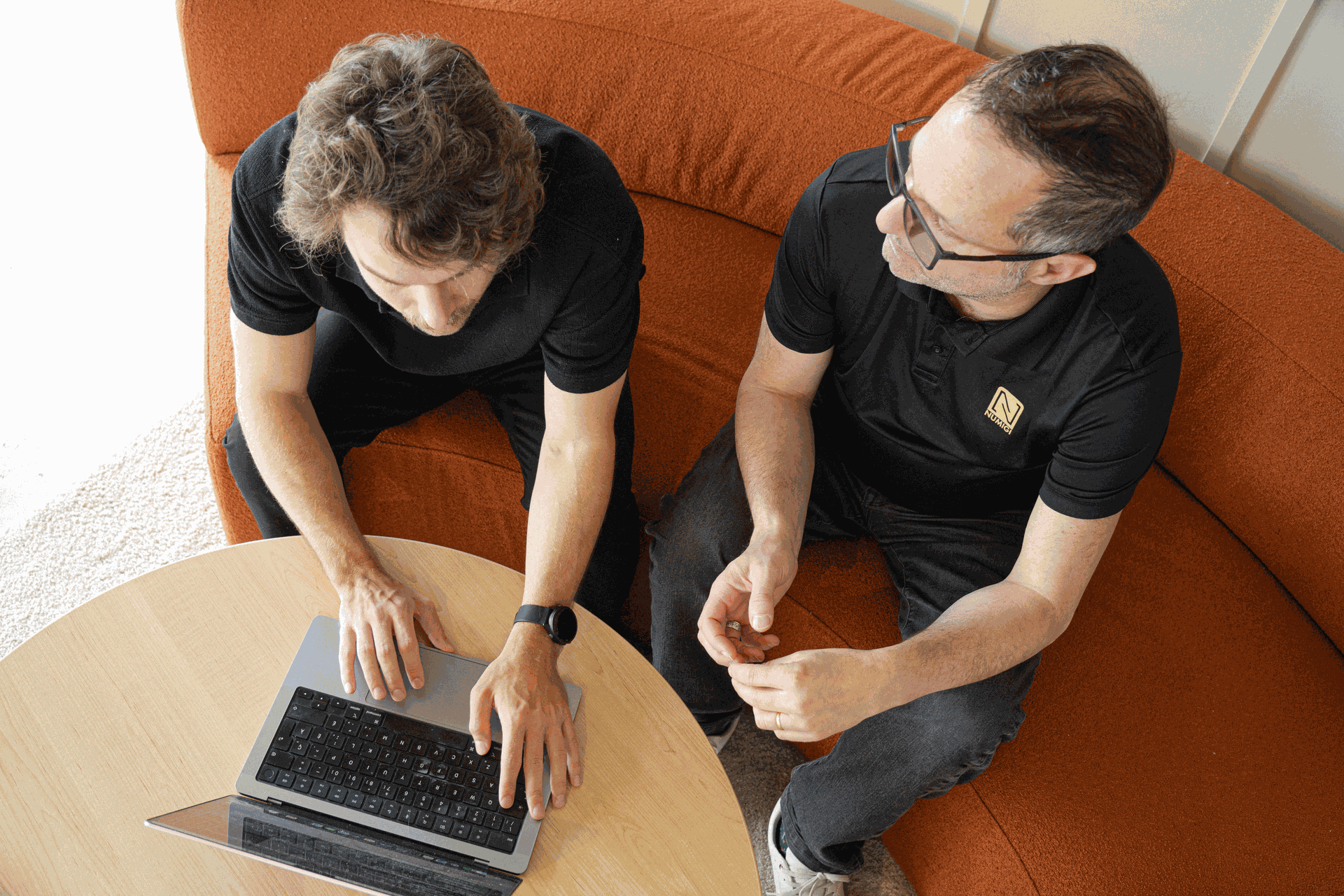 Deux employés de Numigi travaillent sur un canapé avec un MacBook Air