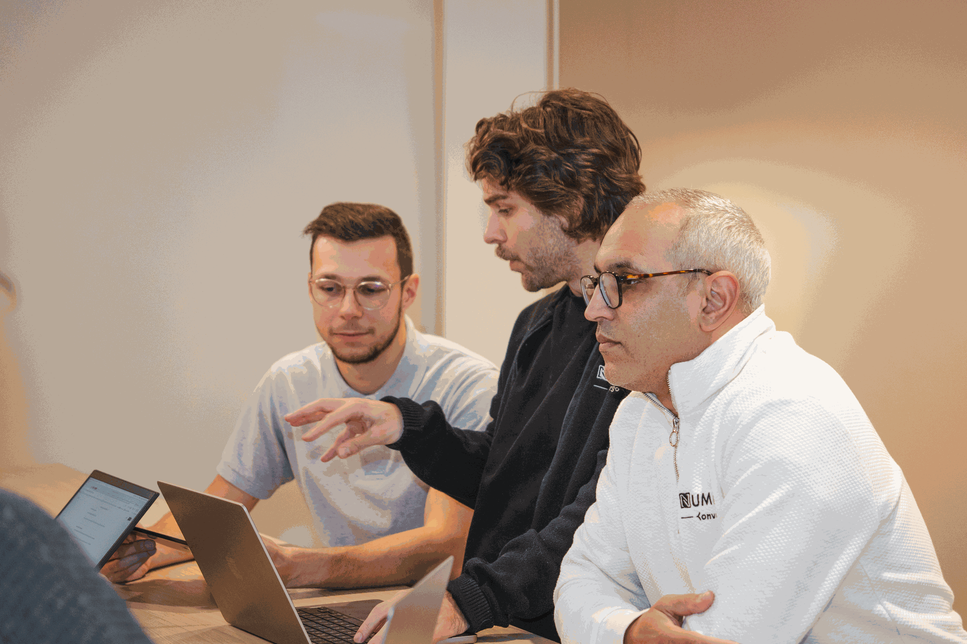 Équipe Numigi collaborant autour d'un bureau dans un espace de travail partagé