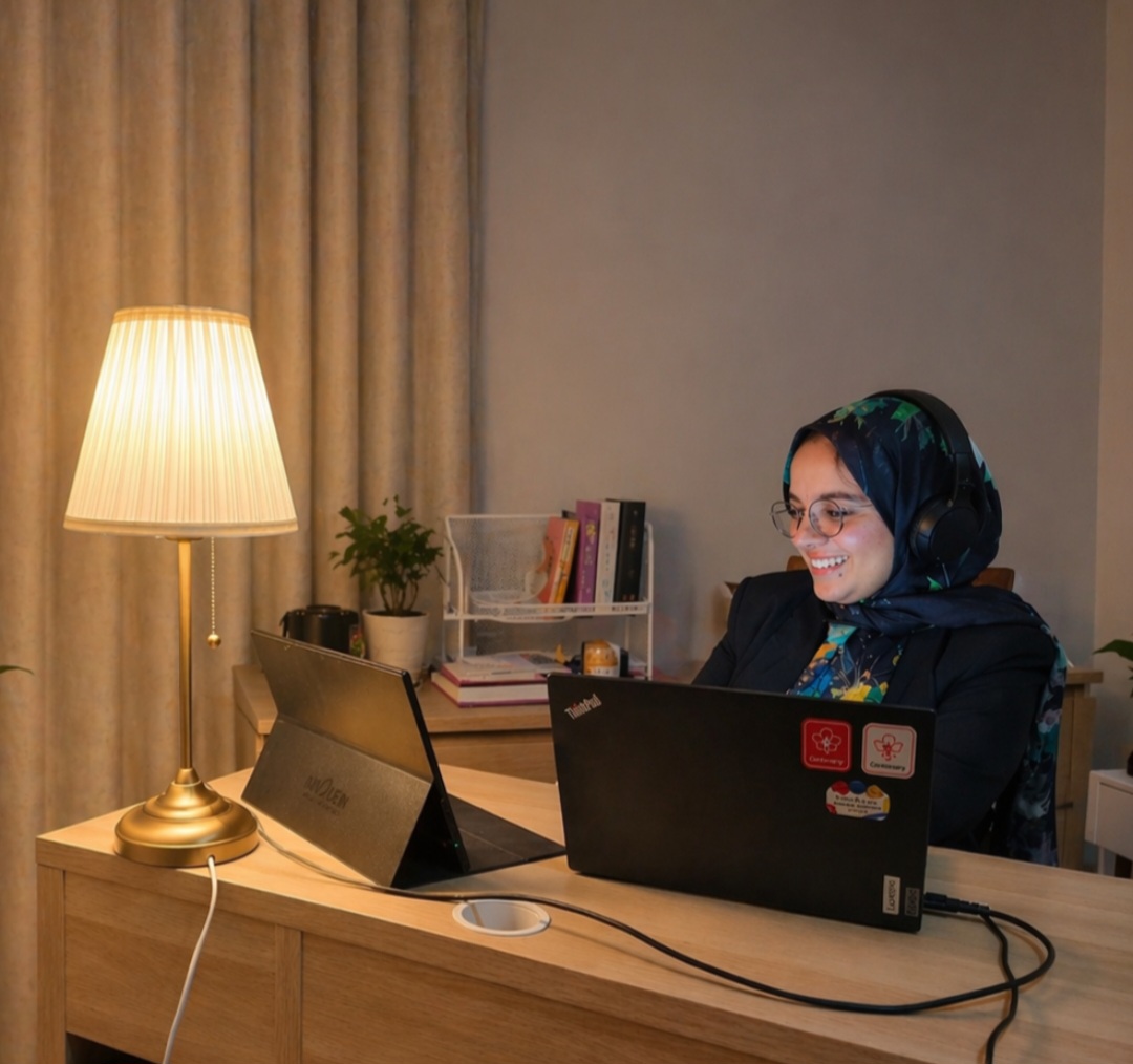Soraya, membre de l'équipe Numigi, souriante et travaillant sur son ordinateur portable à son bureau
